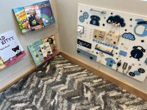 A corner of the Des Moines office featuring a fidget activity board and some children's books.