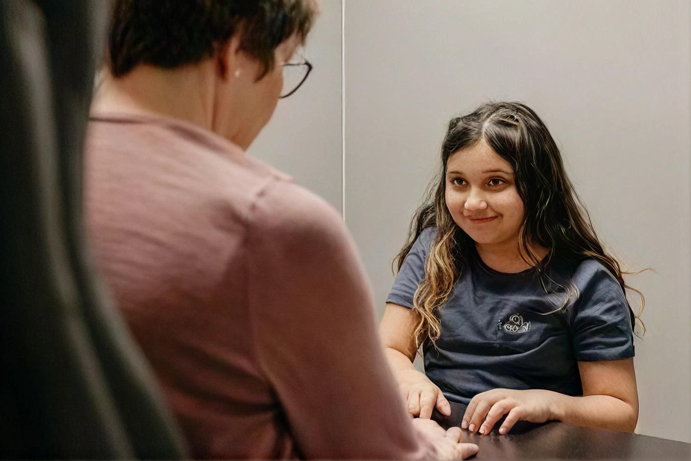 Therapist talking with a preteen girl across a table during a session