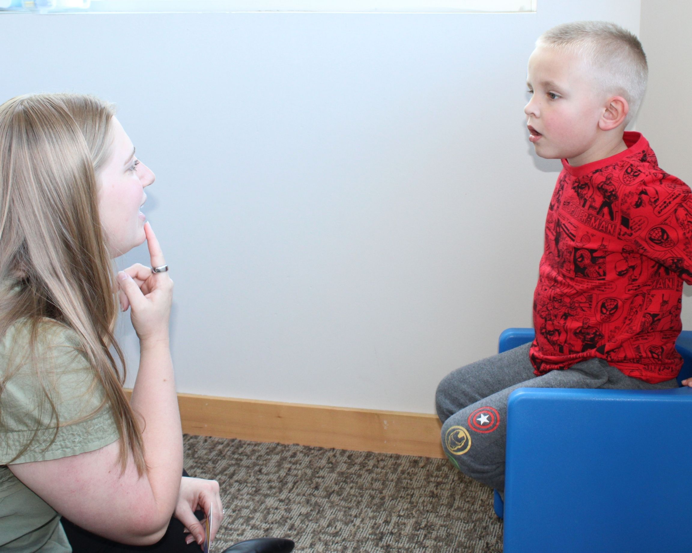Speech-language pathologist reading a book together with a young girl at a table