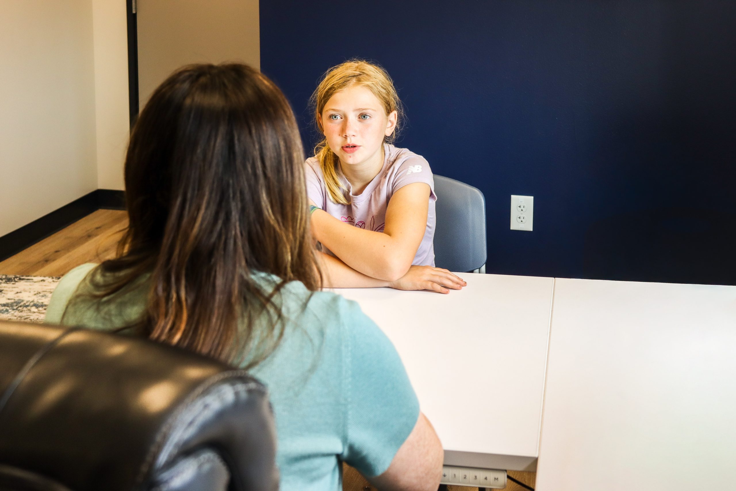 Therapist holding up a happy emotion card for a young boy at a therapy table