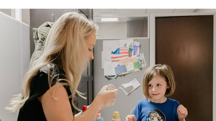 Speech-language pathologist reading a book together with a young girl at a table