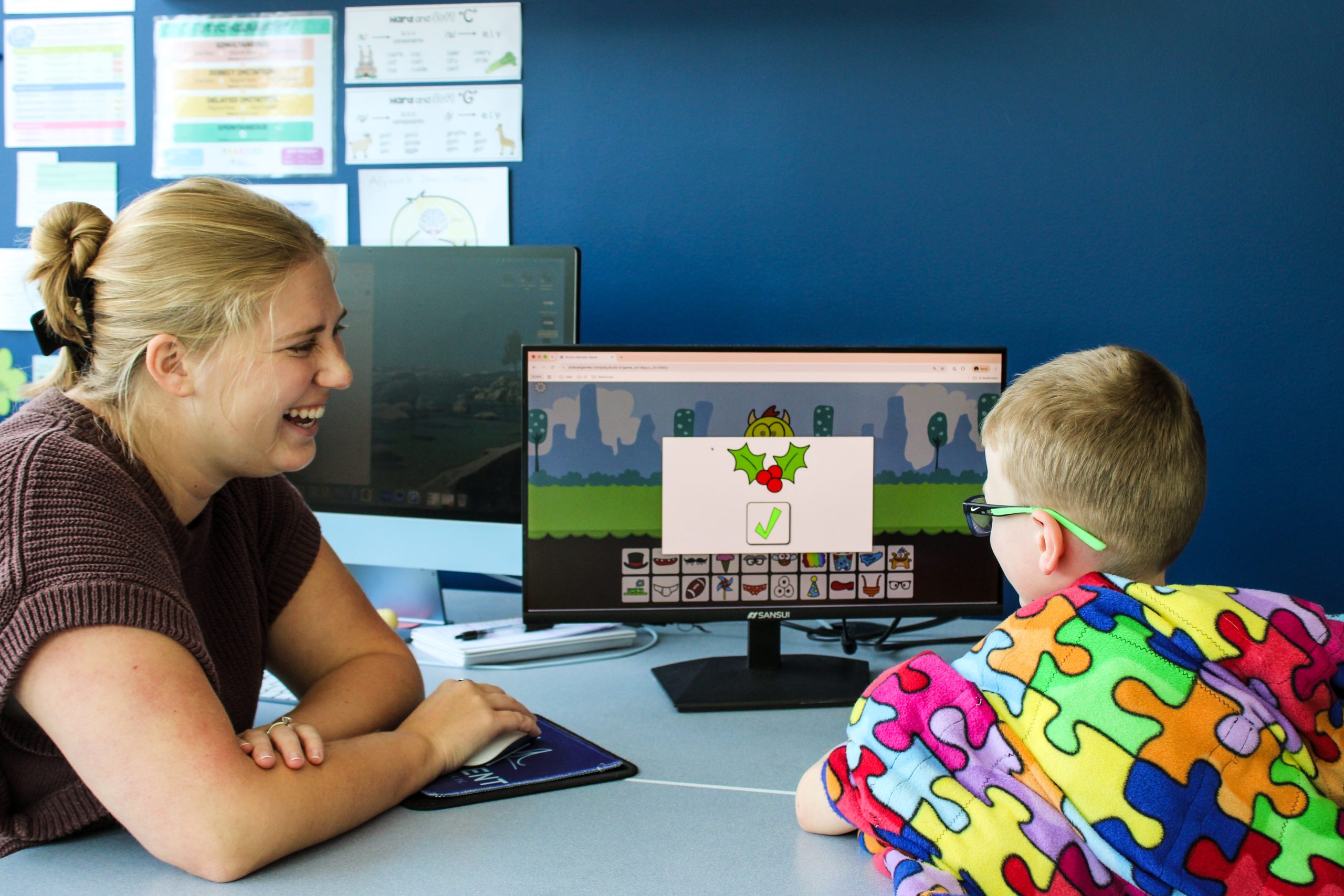 Therapist talking with a young boy while sitting on a colorful play mat