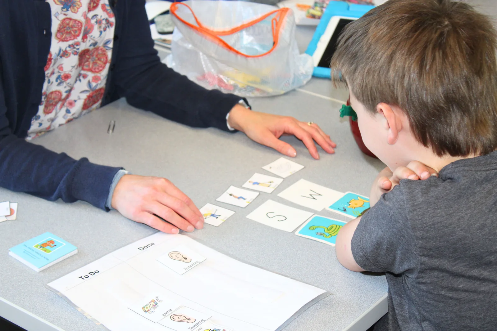 Therapist and young child working through letter and picture cards during an early literacy activity