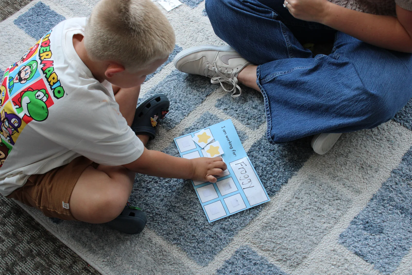 School-age boy working through a visual task card on the floor during a study skills session