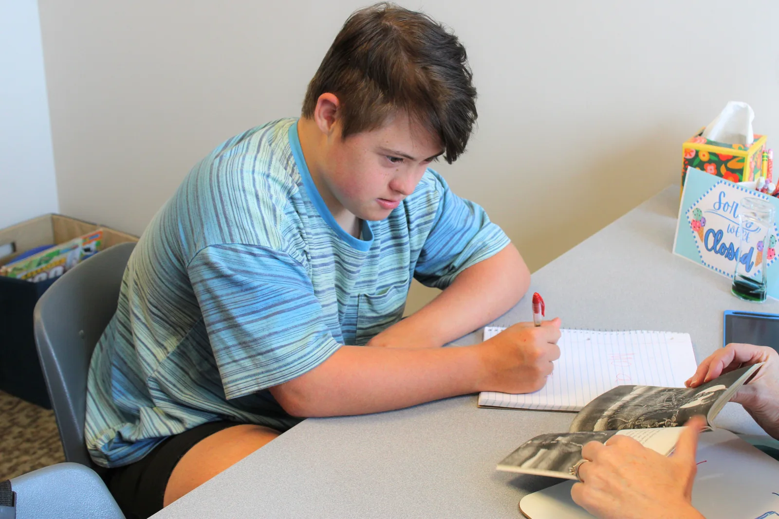 Student writing a story in a notebook during a narrative language session at ETLC
