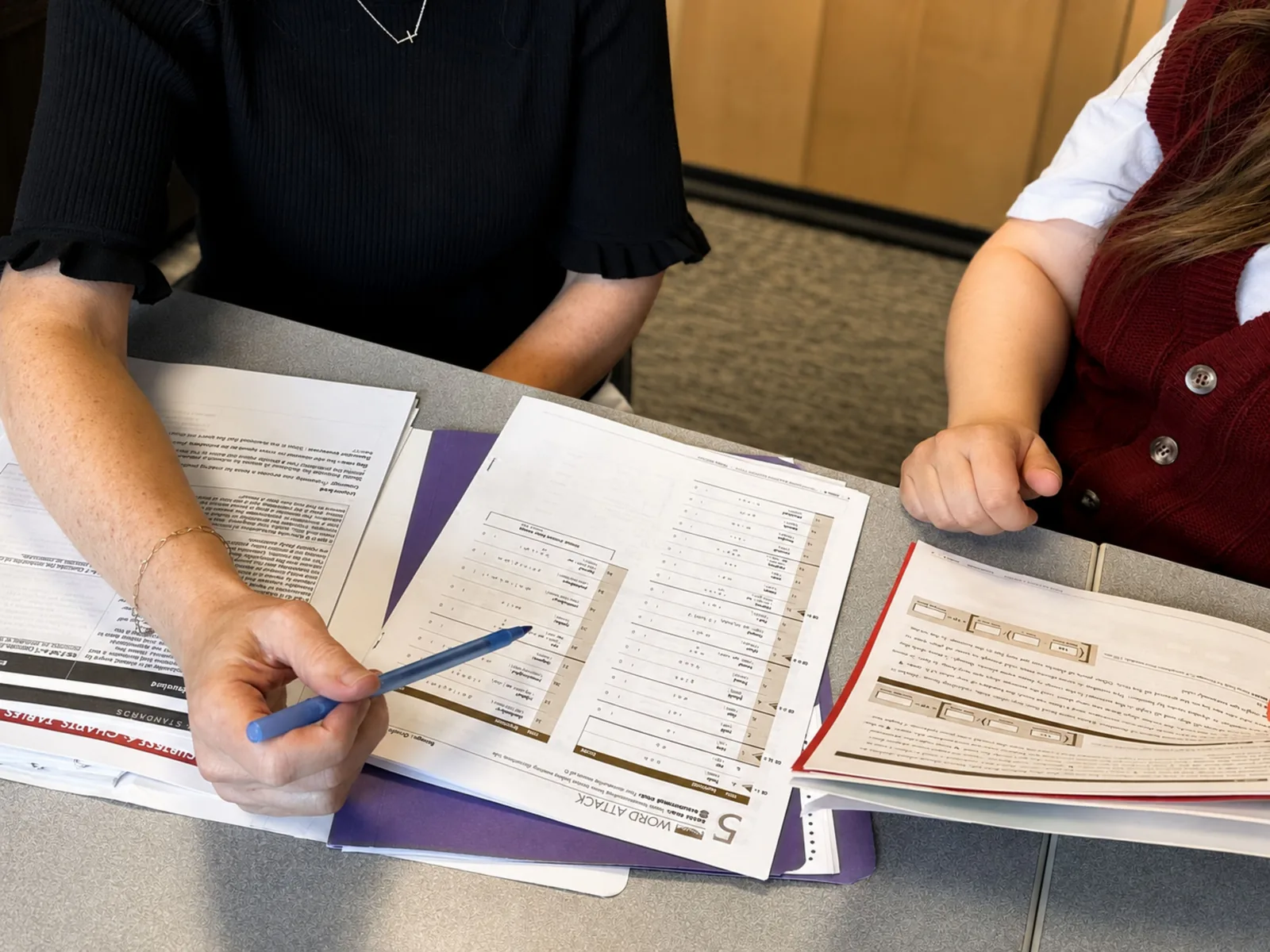 how-to-make-the-most-of-parent-teacher-conferences Parent and teacher reviewing a student’s progress binder and notes during a conference