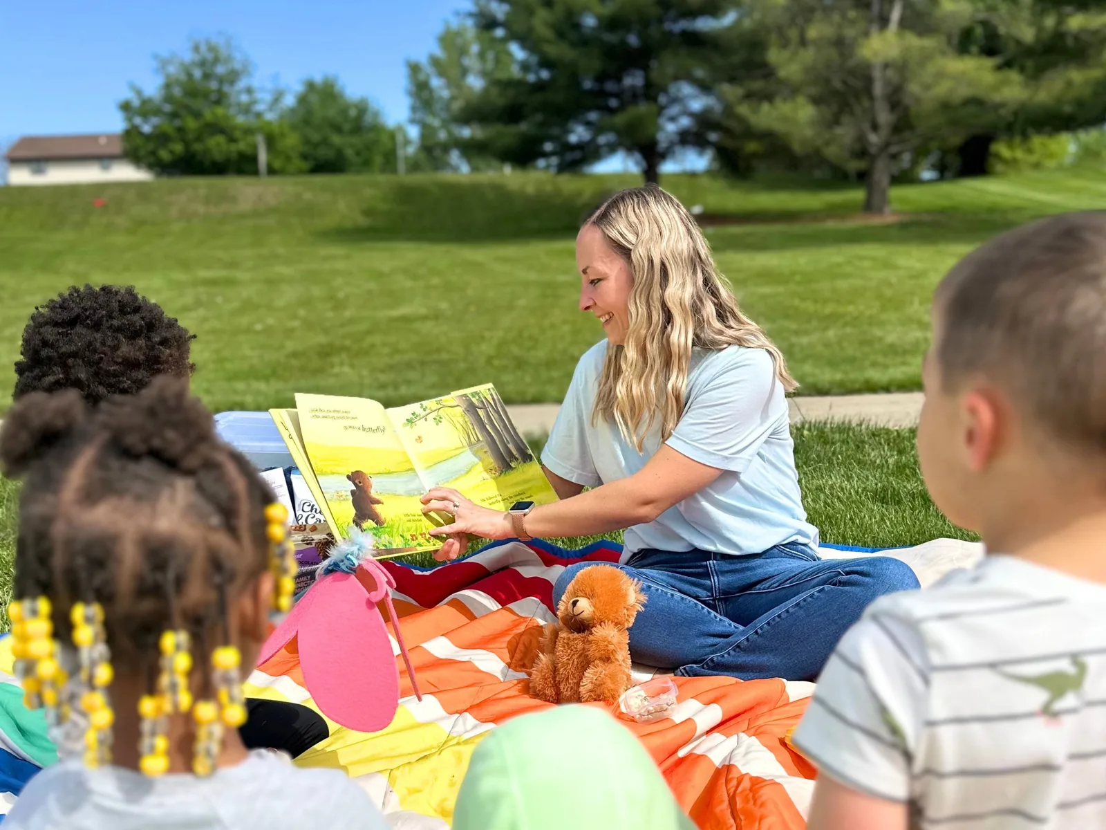 how-to-prevent-the-summer-slide ETLC therapist reading books with children outdoors on a blanket during a summer session