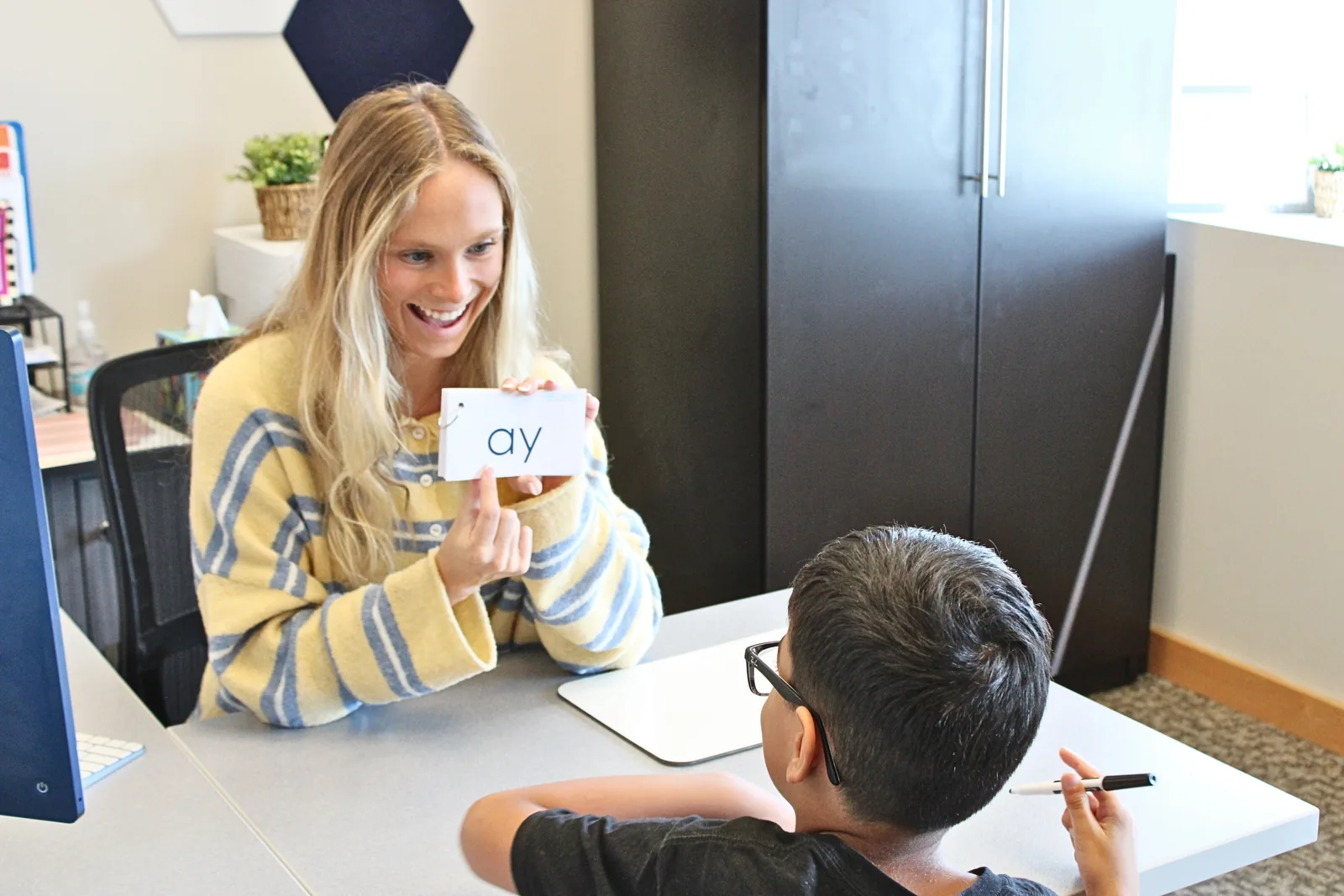 ETLC therapist holding an “ay” phonics card while a student practices decoding
