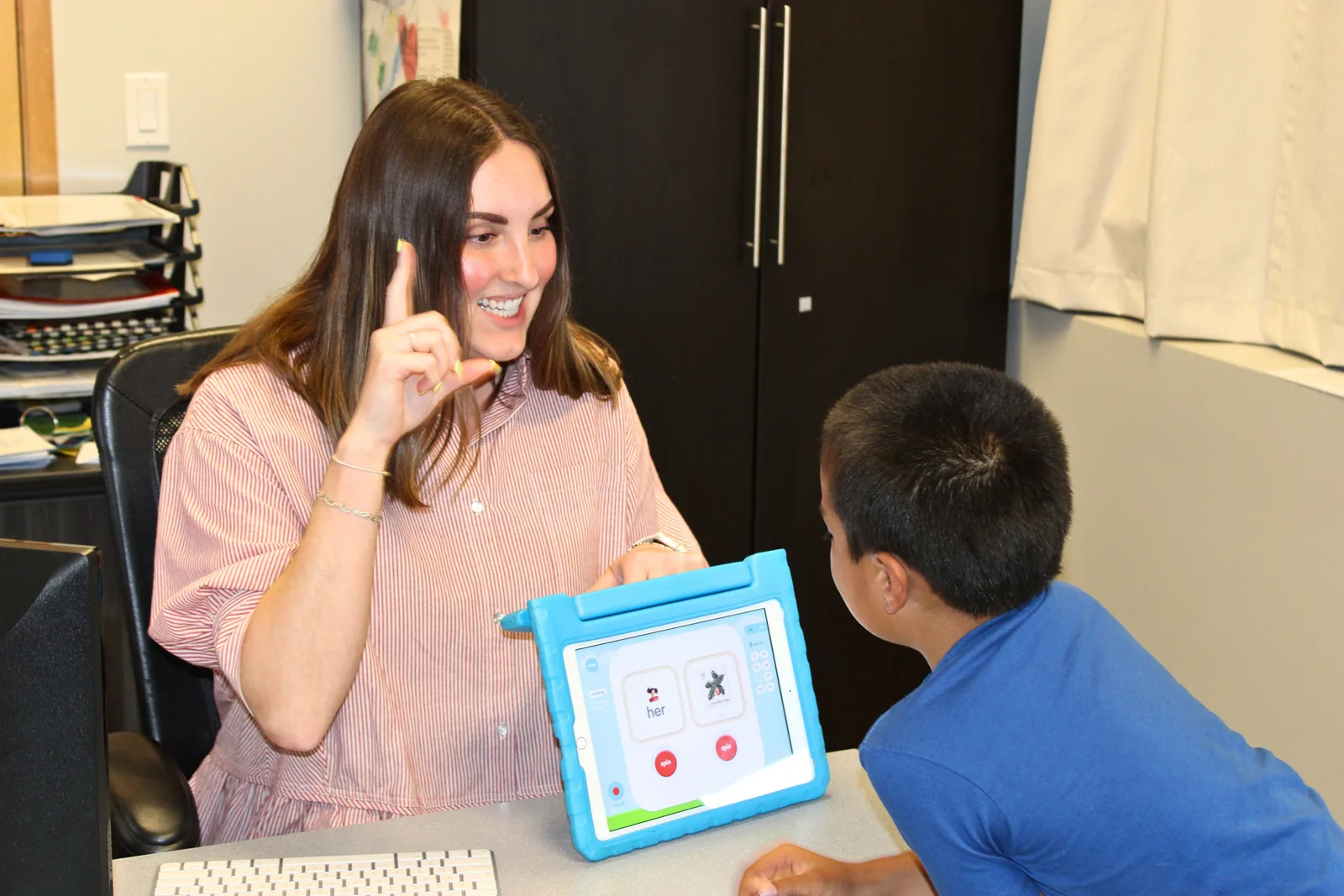 ETLC speech-language pathologist using hand cues and a tablet activity with a young boy