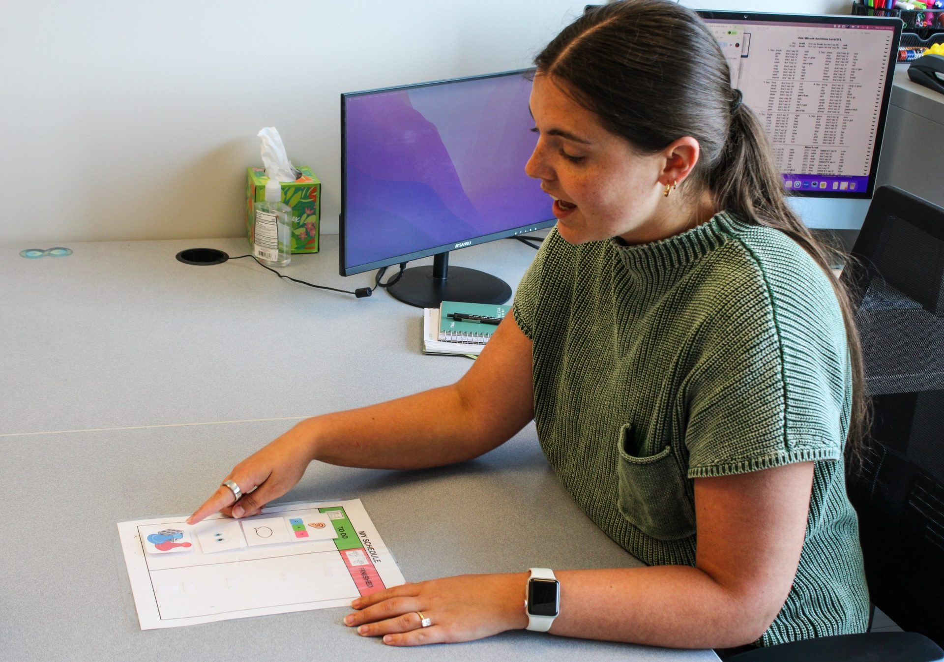 Young boy pointing to a card matching activity while working with a therapist using a visual timer
